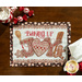 A top-down image of the Baking Up Joy panel placemat on a wooden table, with fabric napkins, peppermint candy, and a mug of hot cocoa peeking into the corners of the frame.