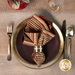 A top down shot of a place setting with the striped fabric of the reversible napkin faced out.