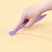 A hand using a purple point turner tool to crease a yellow fabric.