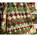 A festive quilt with a patchwork diamond design in red, green, and white, set against a festive backdrop.