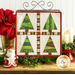 The completed Foundation Paper Piecing Series 2 project for December, an arrangement of four dynamic Christmas trees in red, green, and white fabrics, staged on a rustic wooden tabletop from a craft stand with coordinating decor.