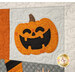 A super close up on the laughing jack o'lantern block, showing fabric, applique, and top quilting details.