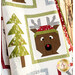 A close up on one of the reindeer and tree blocks, demonstrating fabric, piecing, stitching, inner border, outer border, and topquilting details. The quilt is draped over a wooden ladder to show form and flow.