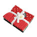 Stack of colorful fabric squares tied with a measuring tape ribbon, featuring floral and honeycomb patterns.