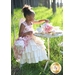 A little girl with a tea set wearing the Tea Party Dress.