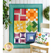 An image of a Learn To Quilt Beginner Quilt hanging on a wall surrounded by greenery.
