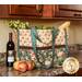 Large cream and teal floral fabric tote with baguettes, flowers, wine bottle, and groceries.