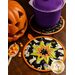 Two Halloween cloth hot pads on a wood table with a pot resting on one