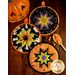 Three Halloween themed cloth hot pads laid flat on a wood table