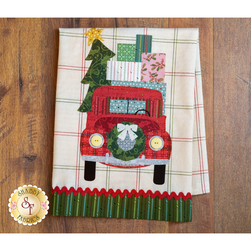 Tea towel with a laser cut vintage truck carrying Christmas presents hung from clothes pins