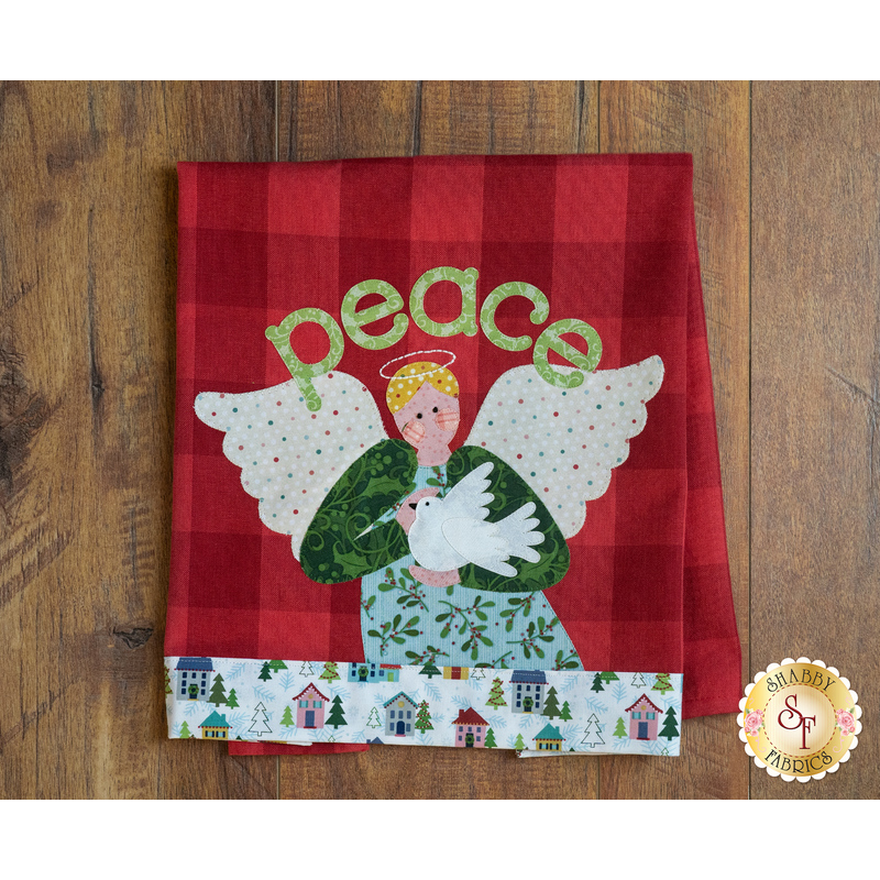 Tea towel with a laser cut angel holding a dove hung from clothes pins