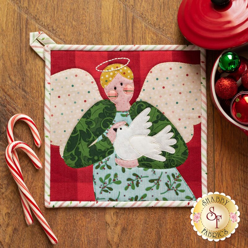 Adorable pot holder with a laser cut applique angel holding a dove on a wood table