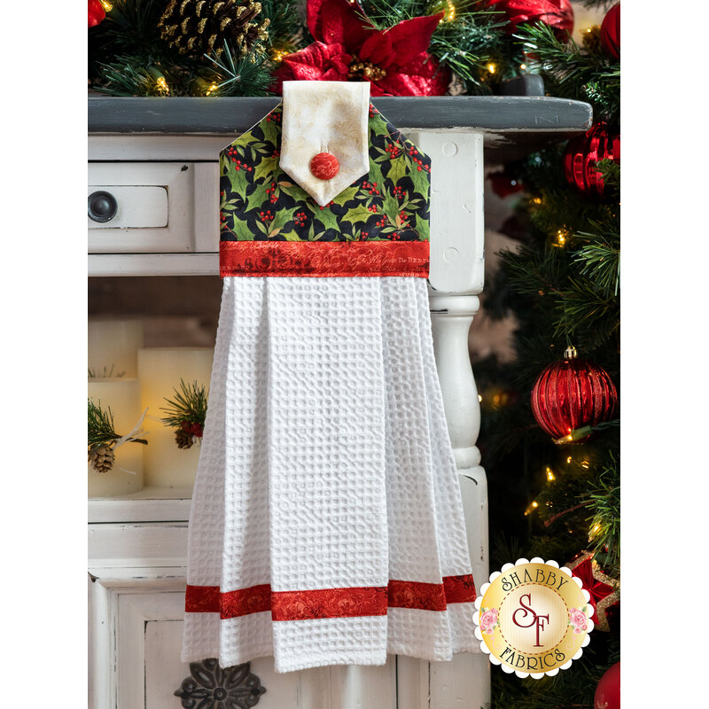 A beautiful black, cream, and red Christmas hanging towel hung from a cabinet