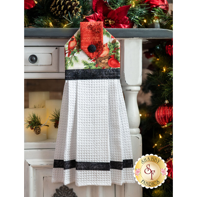 A beautiful black, cream, and red Christmas hanging towel hung from a cabinet