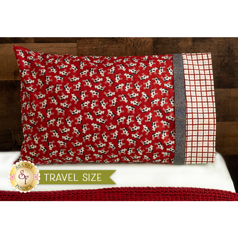 Bright red pillowcase with cows and a fun accent stripe resting on a bed