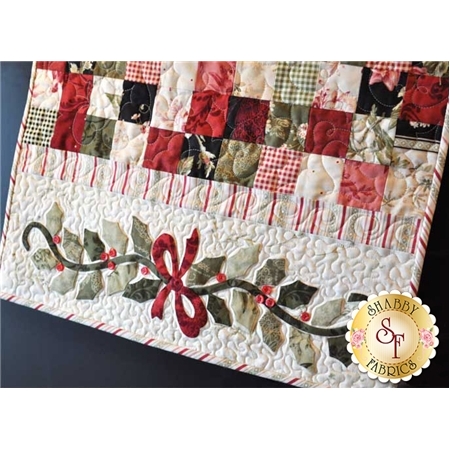 Red, green, and cream patchwork table runner with holly applique and bow.