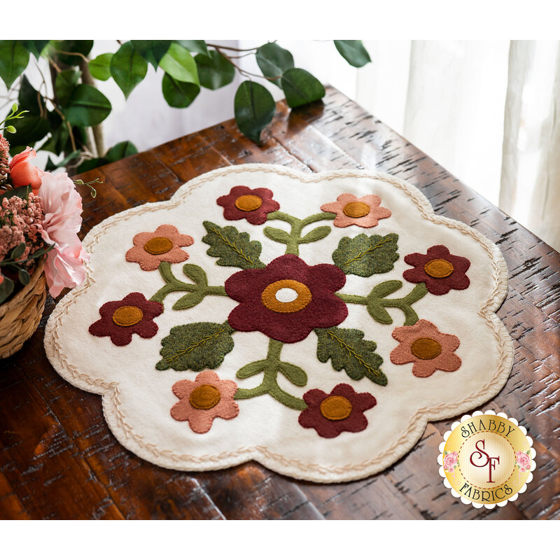 Adorable wool mat with appliqué flowers on a wood desk
