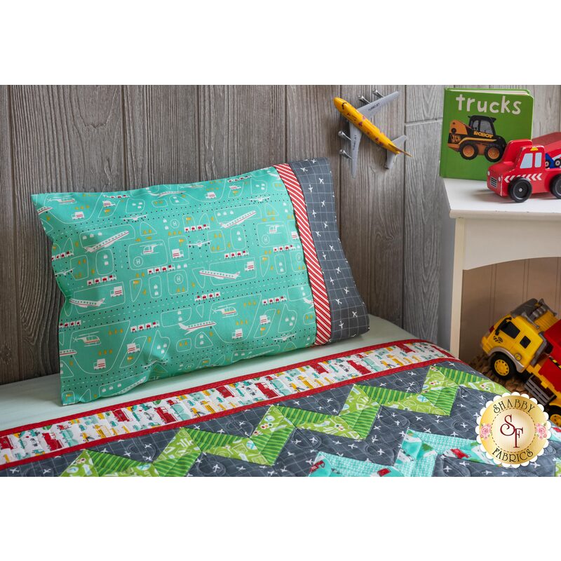 The On The Go Travel Size Pillowcase - Teal Airplanes resting on a kid's bed