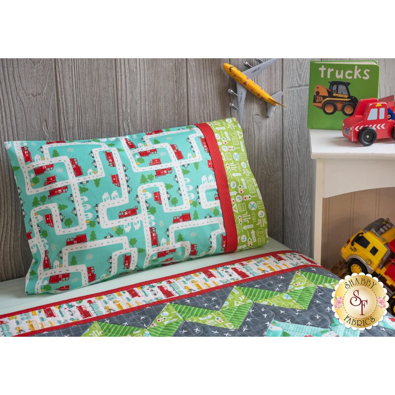 The On The Go Travel Size Pillowcase - Teal Airplanes resting on a kid's bed