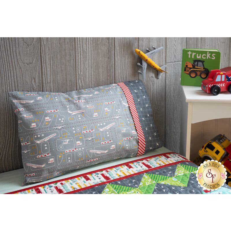The On The Go Travel Size Pillowcase - Teal Airplanes resting on a kid's bed
