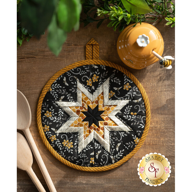 Black, gold, and cream Folded Star Hot Pad laid flat on a wood table