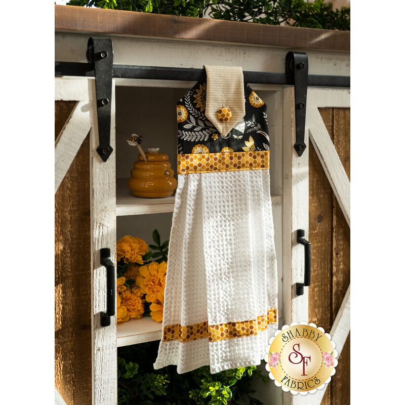 A yellow, black, and cream themed Hanging Towel hung from a cabinet