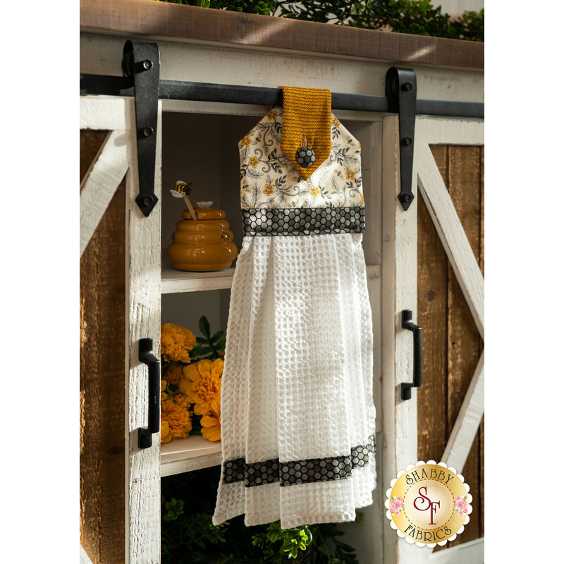 A white, yellow, and black Hanging Towel hung from a cabinet