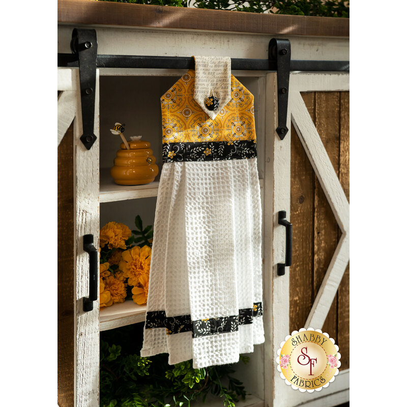 A yellow, white and black Hanging Towel hung from a cabinet