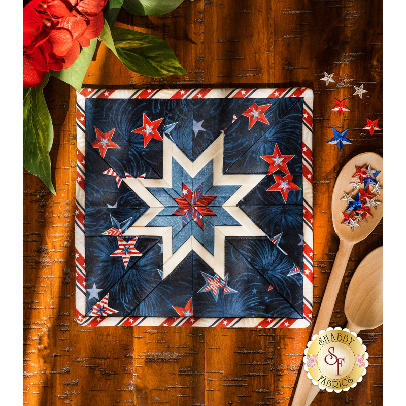 The dark blue Liberty Lane Folded Star Squared Hot Pad on a brown wood table