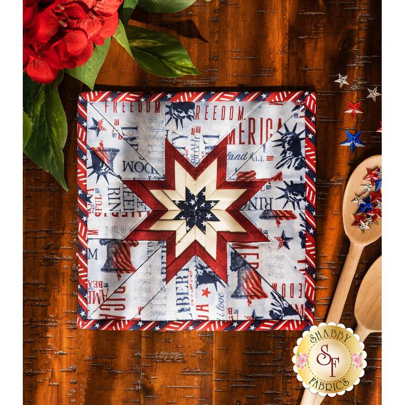 The light blue Liberty Lane Folded Star Squared Hot Pad on a brown wood table