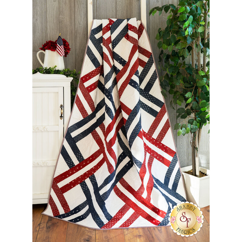 The beautiful Jelly Weave Quilt made with American Gathering fabrics draped over a ladder