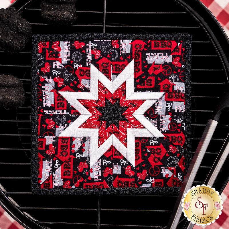 Black and red Peace, Love & BBQ Folded Star Squared Hot Pad laid flat on a BBQ grill