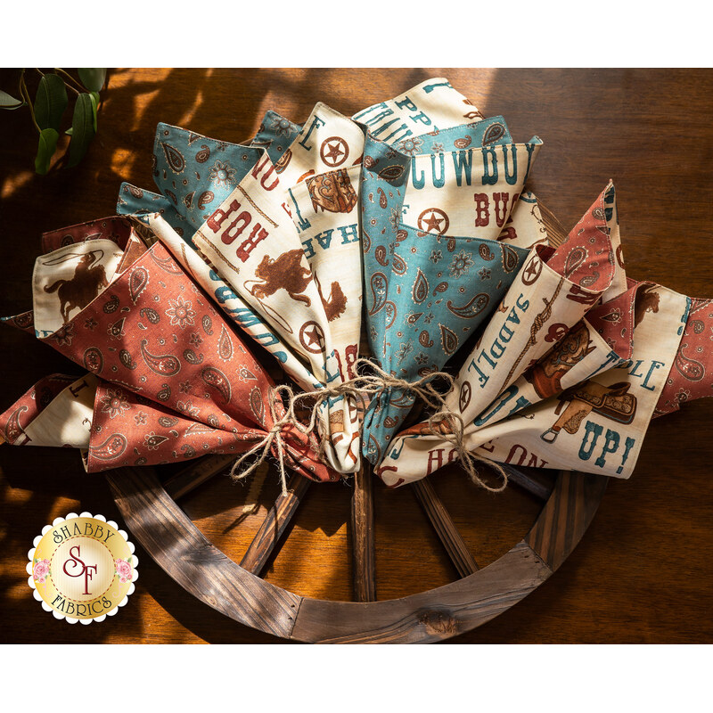 All 4 of the Home On The Range Cloth Napkins displayed on a wooden wagon wheel