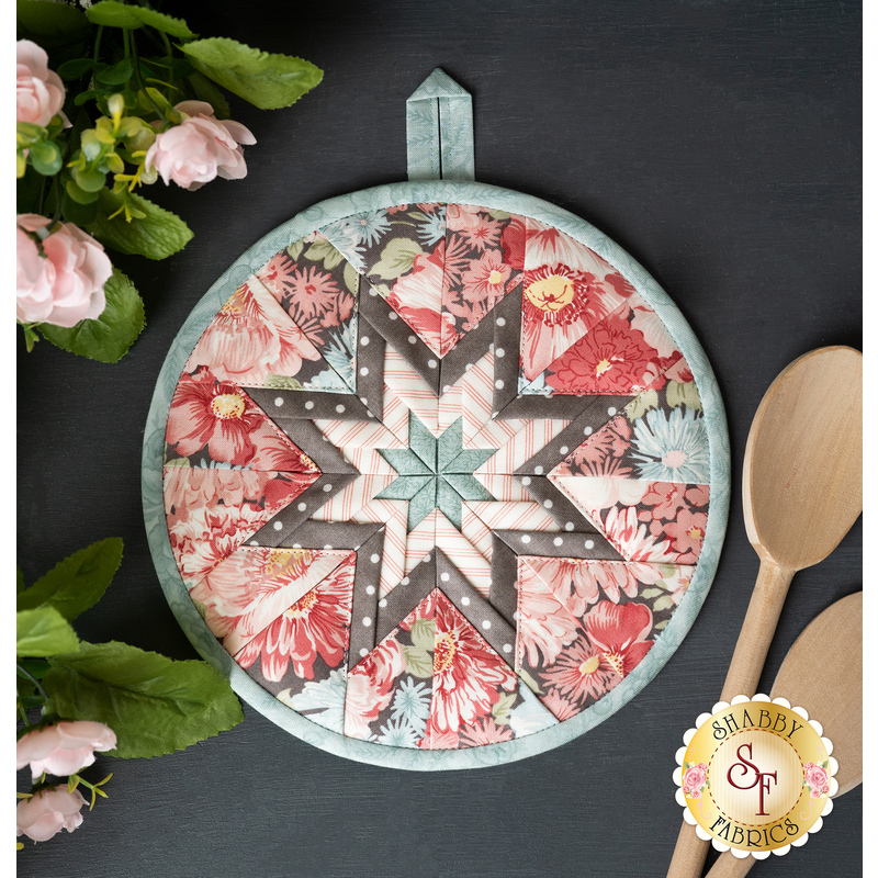 The pale blue and gray floral Folded Star Hot Pad made with Sanctuary fabrics on a dark slate table