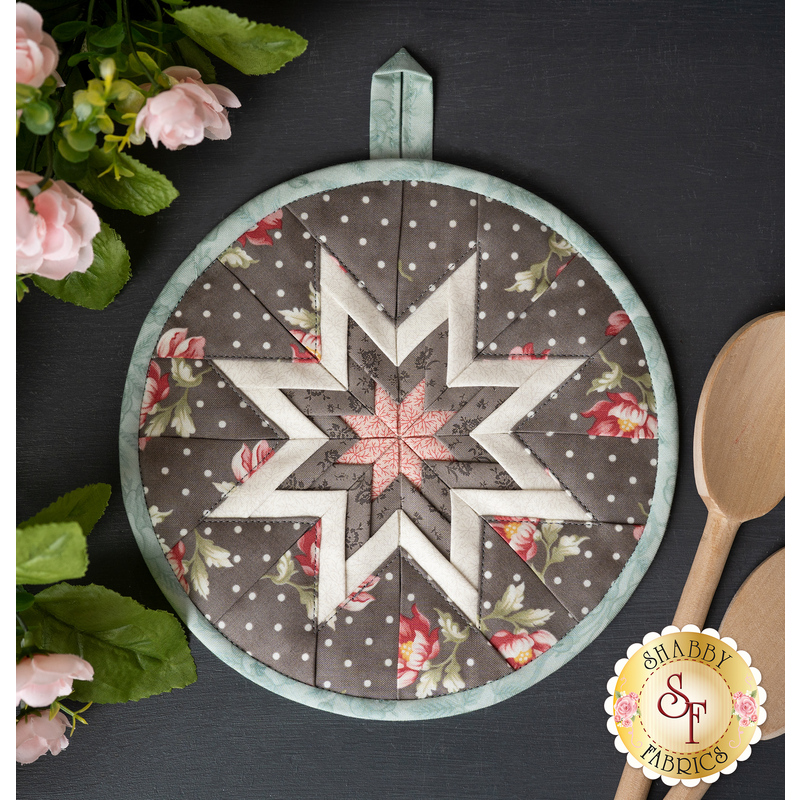 The pale blue and gray polka dot Folded Star Hot Pad made with Sanctuary fabrics on a dark table