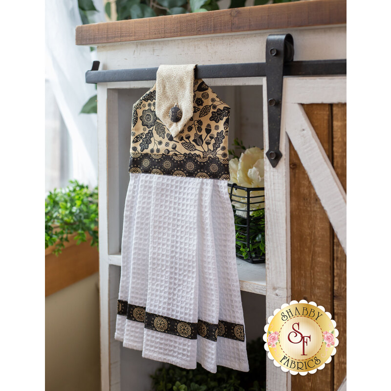 White, tan and black hanging towel hung from a cabinet