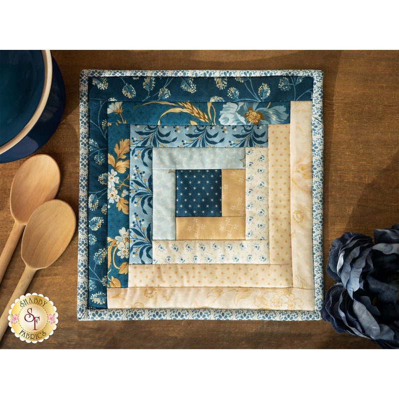 A beautiful Log Cabin Hot Pad made with Perfect Union fabrics laid flat on a wood table