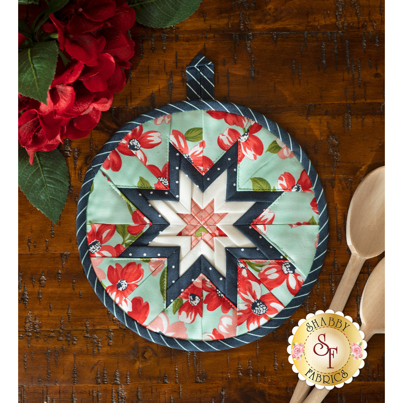 Light teal floral circular hot pad on a wood table