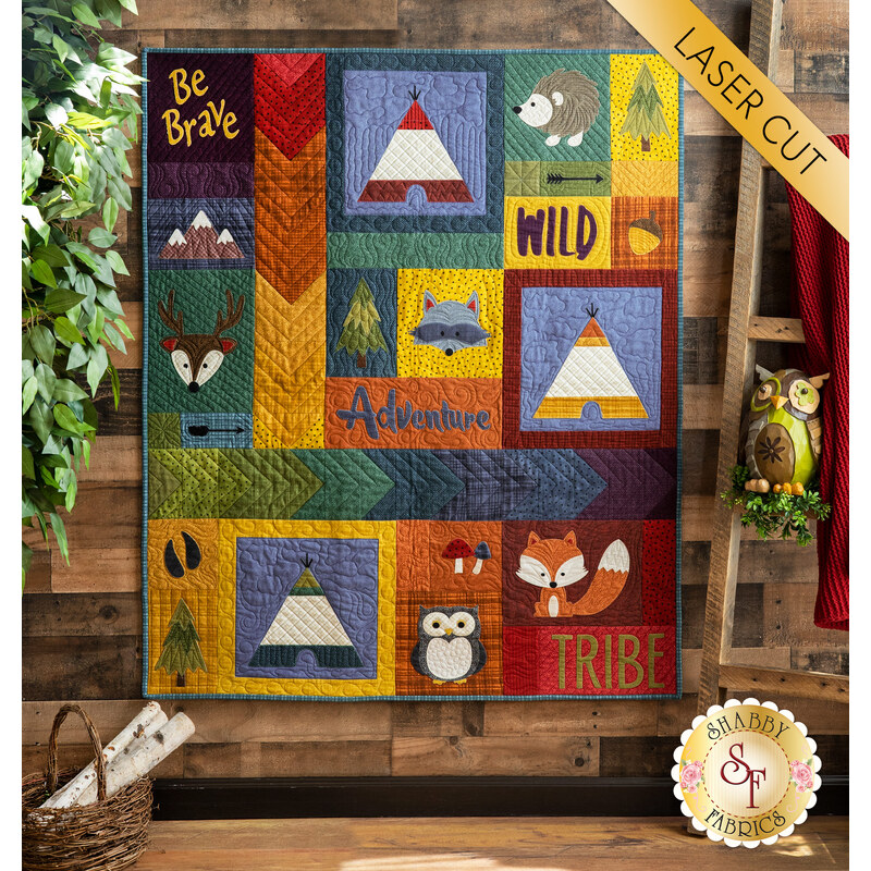 The adorable Adventure With My Tribe Quilt hung from a wooden wall