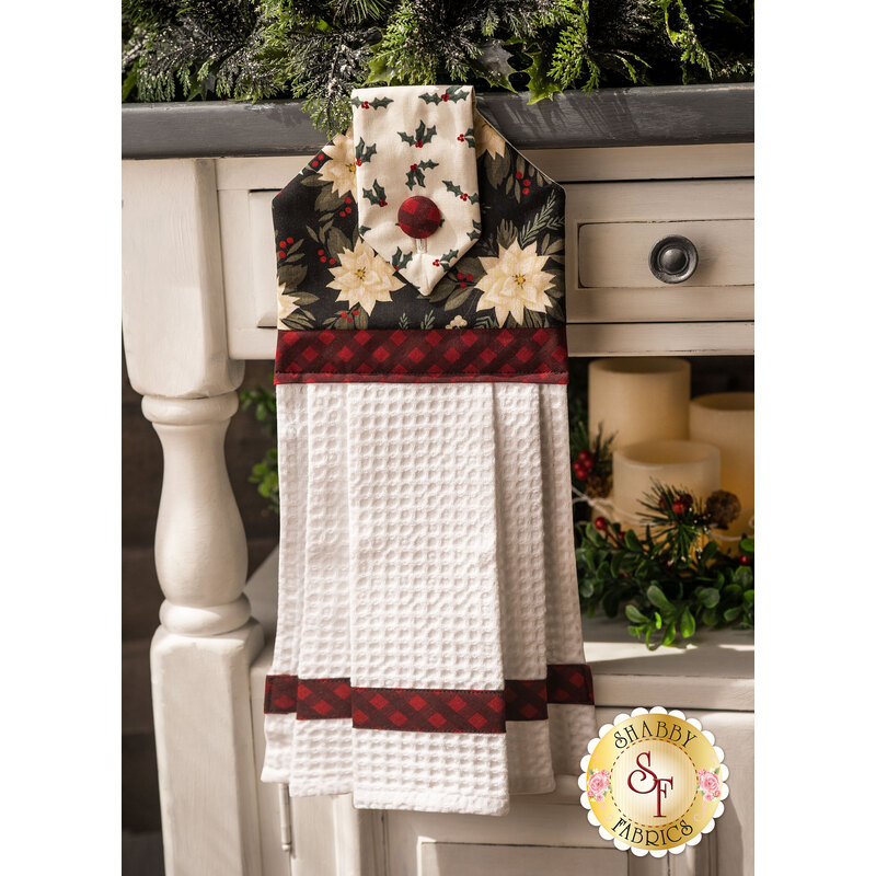 A black, red, and white Christmas hanging towel hung from a cabinet