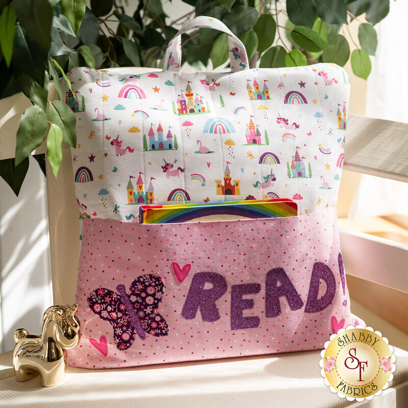 The adorable Unicorn Kingdom Reading Pillow displayed on a chair