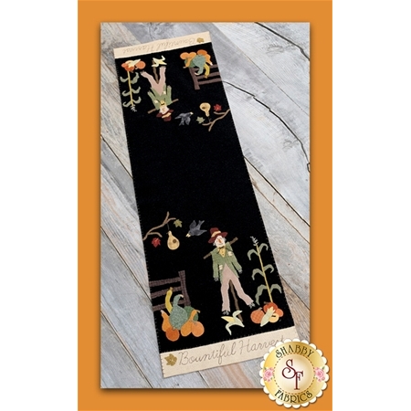 The finished Dear Mister Scarecrow table runner featuring a scarecrow next to a cornstalk, with ears of corn, squash, pumpkins and a fence hear him.