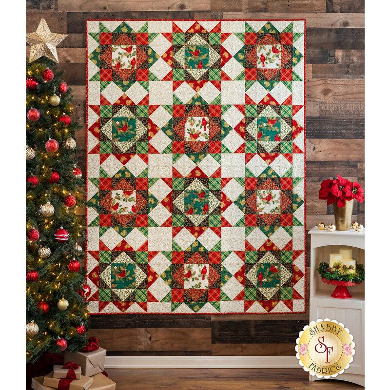 A beautiful Christmas quilt made with Winter's Grandeur fabrics hung on a wall