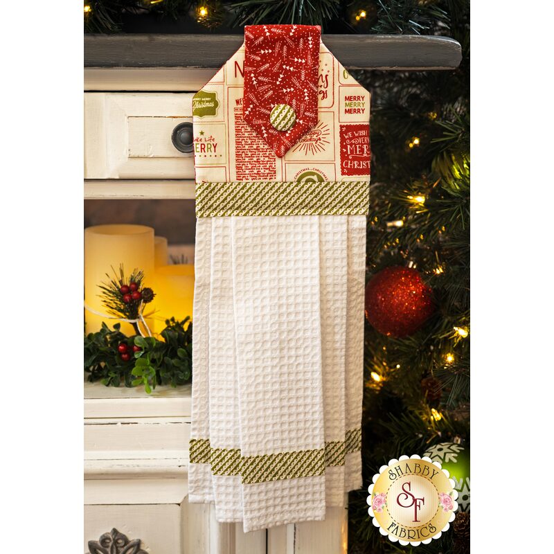 A black, red, and white Christmas hanging towel hung from a cabinet
