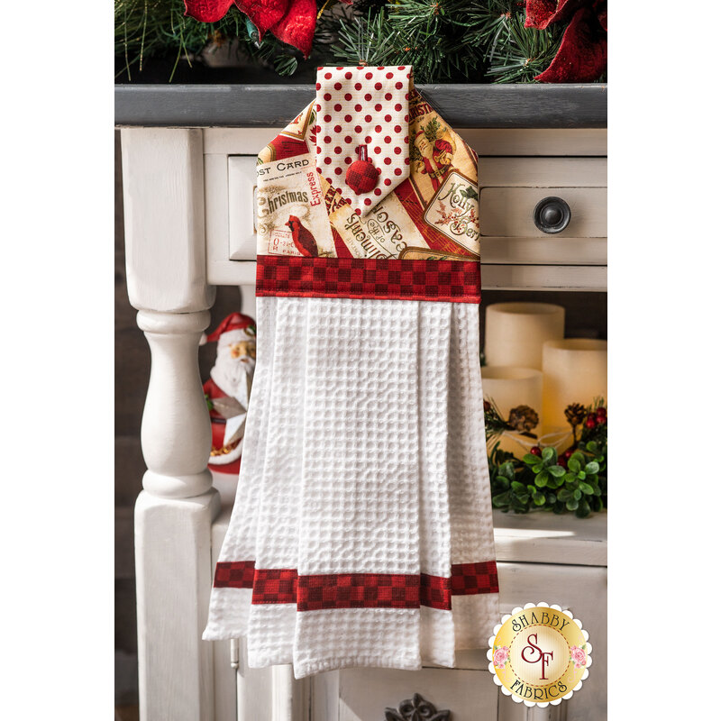A black, red, and white Christmas hanging towel hung from a cabinet