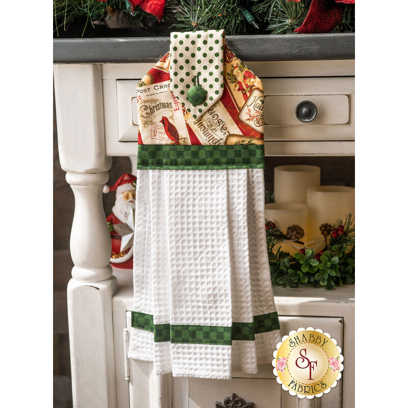 A black, red, and white Christmas hanging towel hung from a cabinet