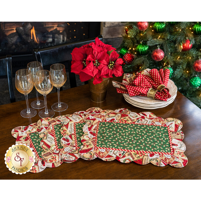 Four beautiful Christmas-themed scalloped placemats on a dark wood table