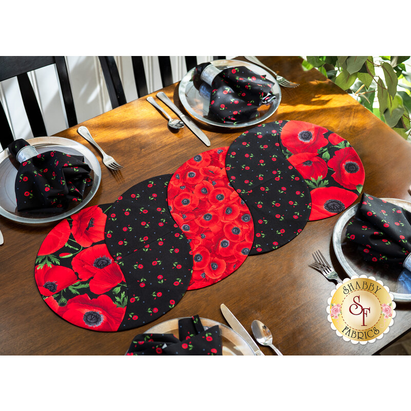 The Braided Twist Table Runner made with Wild Poppy fabrics laid flat on a wood table