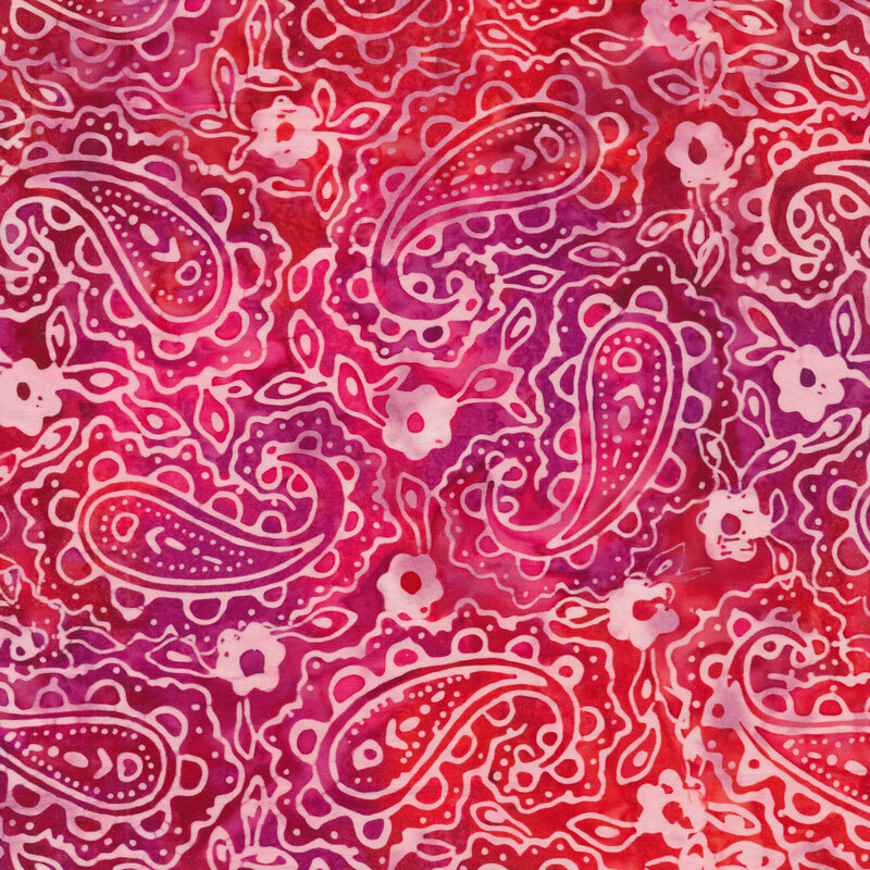 Mottled batik fabric with light pink outlines of batiks and flowers on a dark red background