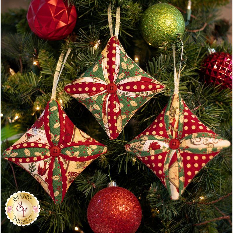Three red and green quilted ornaments in the Cathedral Window style with red central buttons.